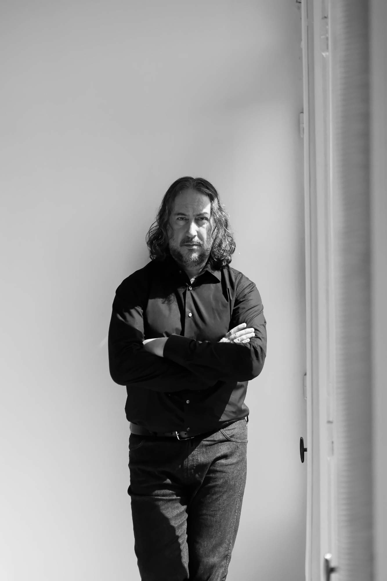 Dimitris Kiriakos standing by a window, black and white portrait